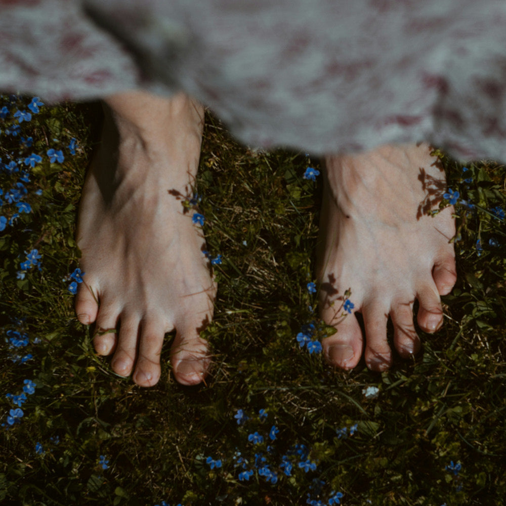 Womans feet on grass and flowers